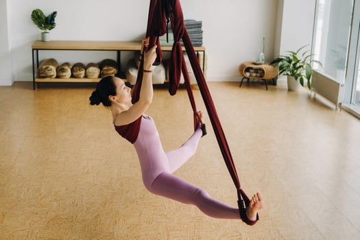 The girl is sitting in a hanging hammock and doing yoga in the gym photo