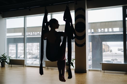 The girl is sitting in a hanging hammock and doing yoga in the gym photo