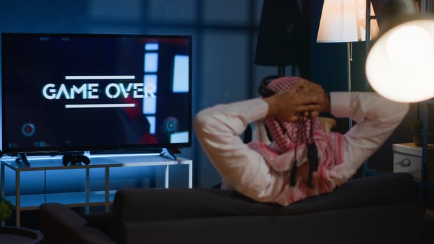 Man playing videogames on TV after long day at work angry after receiging game over screen. Muslim gamer upset after losing at science fiction shooter competition on gaming console photo