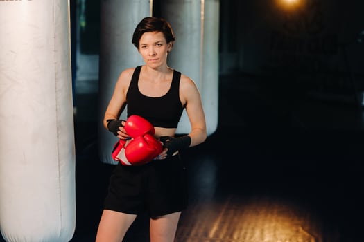 portrait of a female boxer in red gloves in the gym during training photo