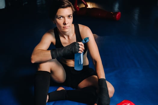 portrait of a female boxer in red gloves in the gym after a workout with a bottle of water photo