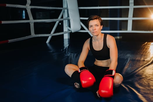 portrait of a female boxer in red gloves in the gym after training photo