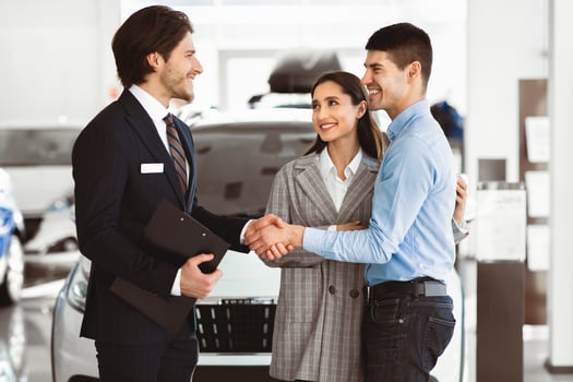 Fair Deal. Happy Man Shaking Hands With Car Sales Manager Buying Auto With Wife In Automobile Dealership Store photo