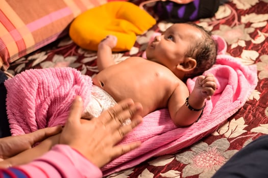 10 Months cute little Indian boy doing oil massage at home by his mother, cute little boy enjoying during oil massage, little toddler enjoying healthy massage by mother photo