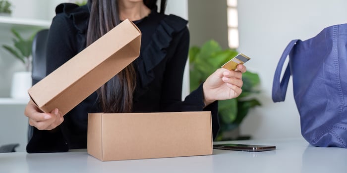 Eager Shopper Unboxing Package with Credit Card in Hand photo