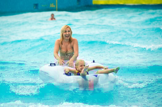 a woman with a child in a rubber inflatable circle plays in the pool of a summer water park in the rain photo