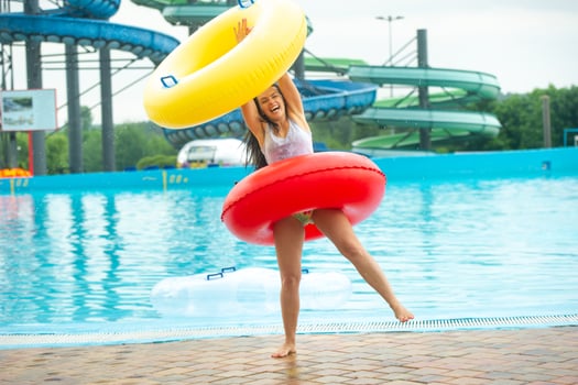 a woman in a swimsuit with rubber inflatable circles plays and has a good time near the pool of the summer water park photo