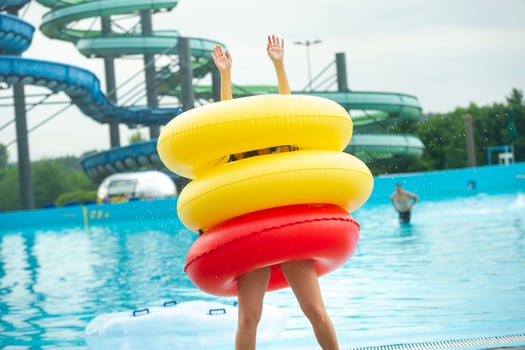 a woman in a swimsuit with rubber inflatable circles plays and has a good time near the pool of the summer water park photo