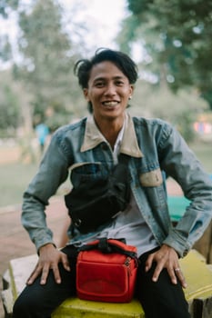 A Southeast Asian man bursts into laughter, showcasing a joyful expression with his head slightly tilted back photo