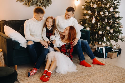 Close-up portrait of a happy family sitting on a sofa near a Christmas tree celebrating a holiday photo