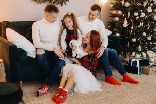 Close-up portrait of a happy family sitting on a sofa near a Christmas tree celebrating a holiday photo