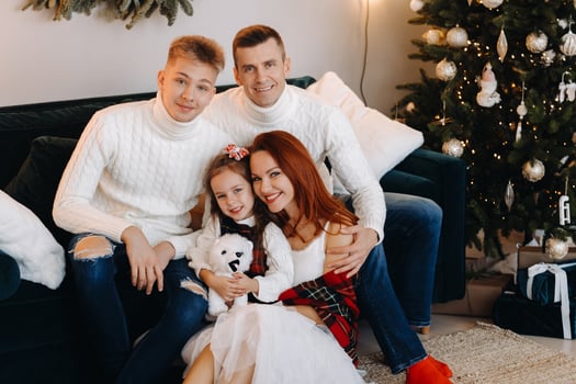 Close-up portrait of a happy family sitting on a sofa near a Christmas tree celebrating a holiday photo