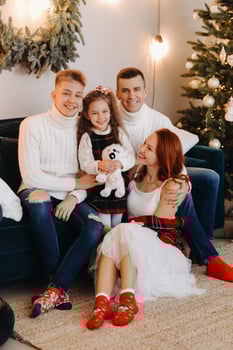 Close-up portrait of a happy family sitting on a sofa near a Christmas tree celebrating a holiday photo