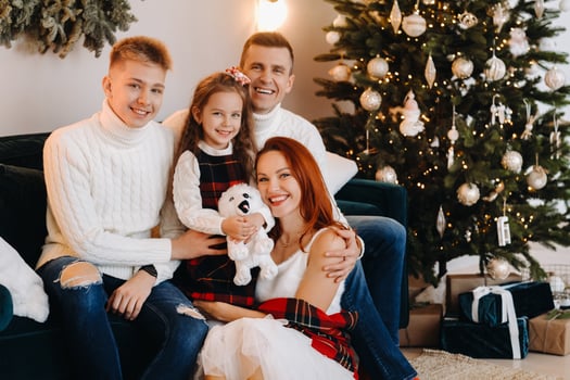 Close-up portrait of a happy family sitting on a sofa near a Christmas tree celebrating a holiday photo
