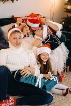 Close-up portrait of a happy family sitting on a sofa near a Christmas tree celebrating a holiday photo