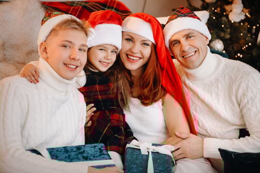 Close-up portrait of a happy family sitting on a sofa near a Christmas tree celebrating a holiday photo