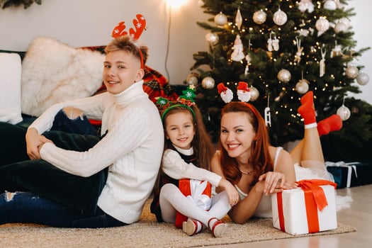 a happy family is lying on the floor of the house with New Year's gifts, next to the Christmas tree photo