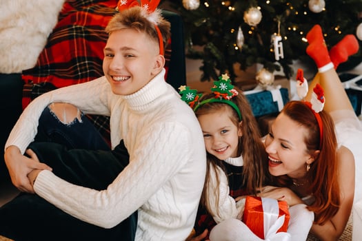a happy family is lying on the floor of the house with New Year's gifts, next to the Christmas tree photo