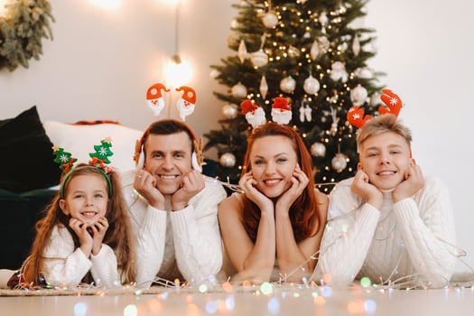 Close-up portrait of a happy family lying near a Christmas tree celebrating a holiday photo