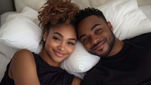 Couple smiling together on a cozy bed, enjoying a relaxed moment in the soft morning light photo