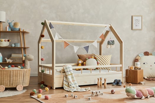 Creative composition of cozy scandinavian child's room interior with wooden bed, plush and wooden toys and textile hanging decorations. Neutral creative wall, carpet on the parquet floor. Template. photo