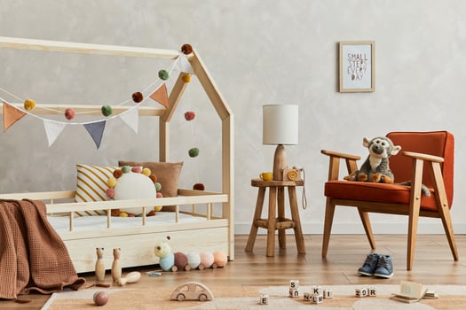 Creative composition of cozy scandinavian child's room interior with wooden bed, red armchair, plush and wooden toys and textile hanging decorations. Creative wall, carpet on the floor. Template. photo