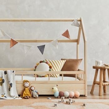 Creative composition of cozy scandinavian child's room interior with wooden bed, plush and wooden toys and textile hanging decorations. Neutral creative wall, carpet on the parquet floor. Template. photo