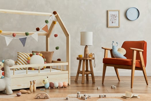 Stylish composition of cozy scandinavian child's room interior with wooden bed, red armchair, plush and wooden toys and textile hanging decorations. Creative wall, carpet on the floor. Template. photo