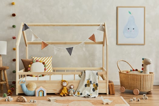 Stylish composition of cozy scandinavian child's room interior with wooden bed, plush and wooden toys, rattan basket and textile hanging decorations. Creative wall, carpet on the floor. Template. photo