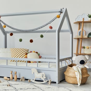 Stylish scandinavian child's room with creative wooden bed, pillows, wooden shelf, plush and wooden toys and hanging textile decorations. Grey walls, carpet on the floor. Template. photo