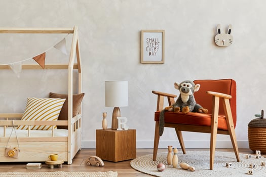 Stylish composition of cozy scandinavian child's room interior with bed, red armchair, plush and wooden toys and textile hanging decorations. Creative wall, carpet on the floor. Copy space. Template. photo