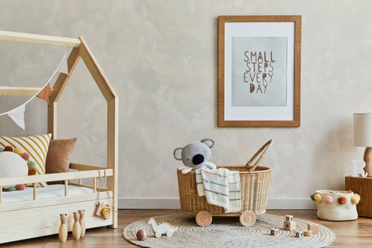 Stylish composition of cozy scandi child's room interior with mock up poster frame, bed, rattan basket, plush and wooden toys and decorations. Creative wall. Copy space. Template. photo