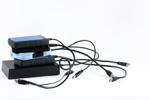 many external hard drives with wires lie on a white background. Hard drives on isolate. photo
