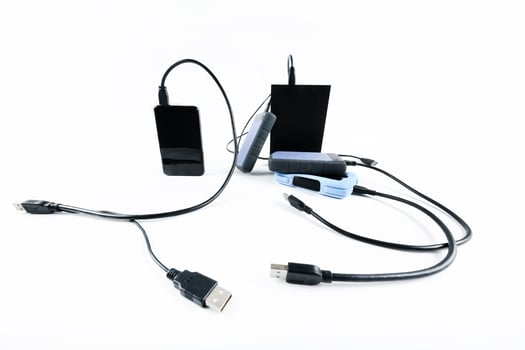 many external hard drives with wires lie on a white background. Hard drives on isolate. photo