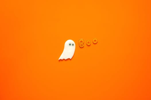 Halloween background with gel stickers of white ghost sheet and alphabets on orange background. Minimal concept. photo