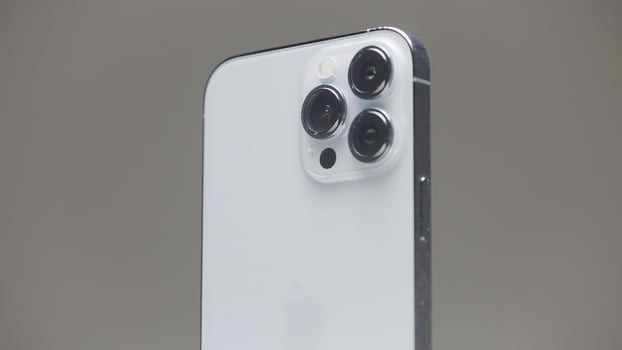 Germany - Berlin, September 27, 2022. New iPhone 13 pro rotating slowly isolated on a grey wall background. Action. Stylish exterior design of new iPhone with metal case and three cameras. photo