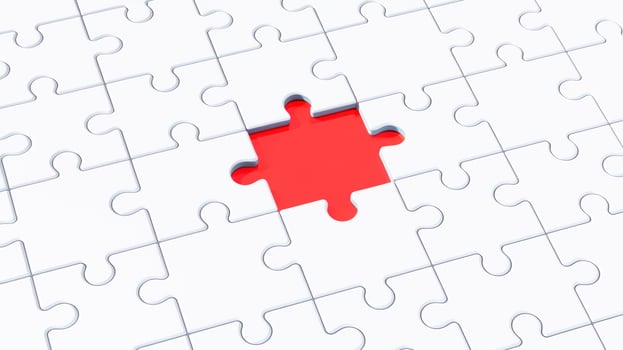 blank white jigsaw puzzle with one final missing piece showing empty red background underneath photo