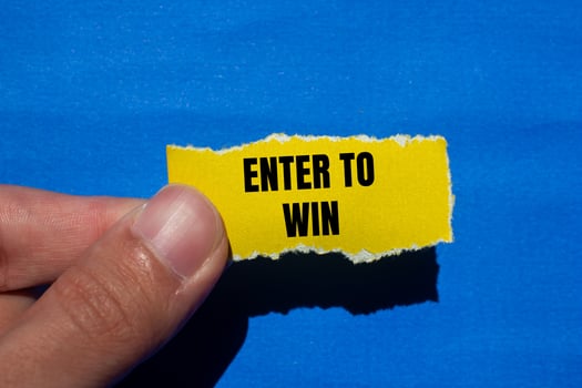 Enter to win message written on ripped torn yellow paper with blue background. Conceptual enter to win symbol. Copy space. photo