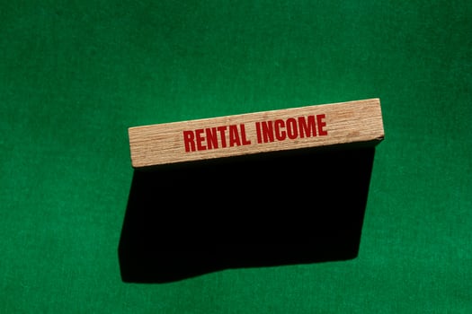 Rental income message written on wooden block with green background. Conceptual rental income symbol. Copy space. photo