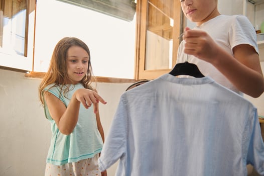 Siblings choosing clothes together in a bright room photo