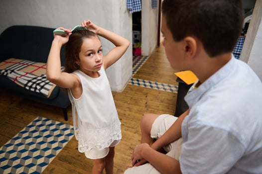 Young girl brushing hair while talking to brother indoors photo