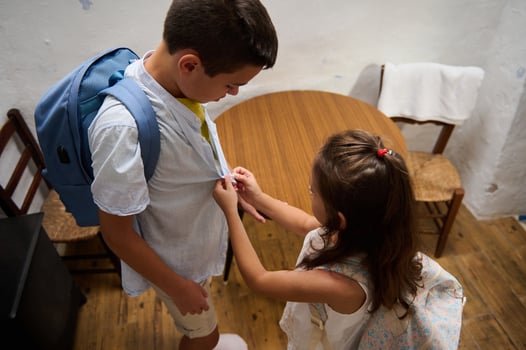 Young siblings helping each other get ready for school photo