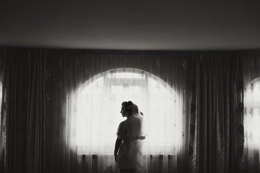 A woman in a wedding dress stands in front of a window photo
