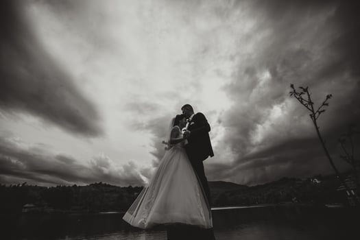 A couple is kissing in the rain, with a cloudy sky in the background photo