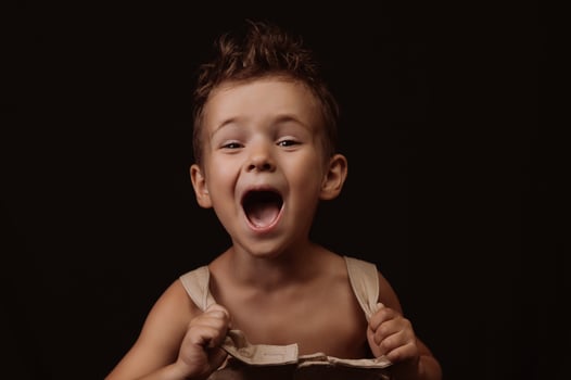 happy boy in overalls with stylish hairstyle screams photo