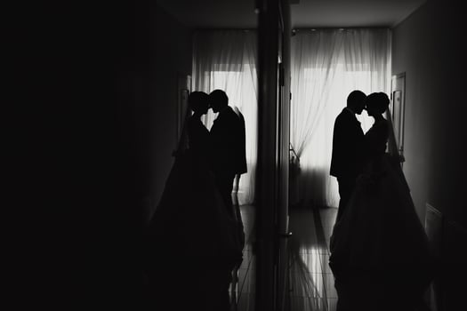 A couple is kissing in a room with a window photo
