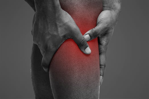 Sport trauma. Cropped of black man massaging his sore injured leg, white background photo