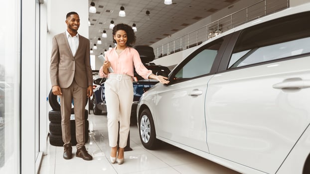 Buying Car. African American Businessman Choosing Auto With Female Dealer Walking In Dealership Store. Panorama, Empty Space photo