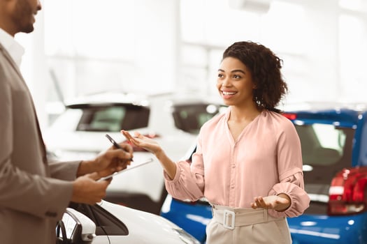 Car Buyer. Cheerful Lady Customer Talking With Auto Seller Guy Standing In Automobile Dealership Shop. Selective Focus photo