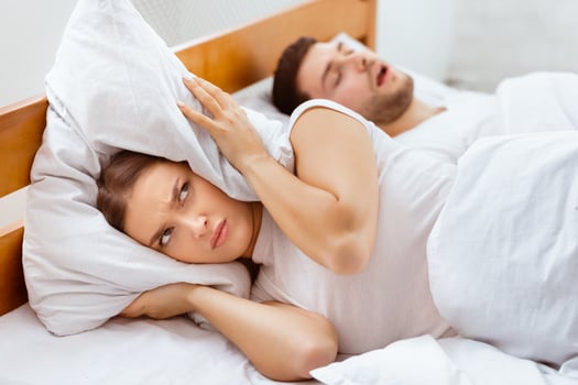 Snoring Concept. Irritated Woman Covering Ears With Pillow Lying Near Sleeping Husband Unable To Sleep In Bed Indoor. Selective Focus photo